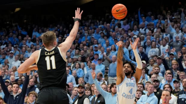 RJ Davis (4) shoots a three-point shot against Wake Forest Demon Deacons forward Andrew Carr (11)